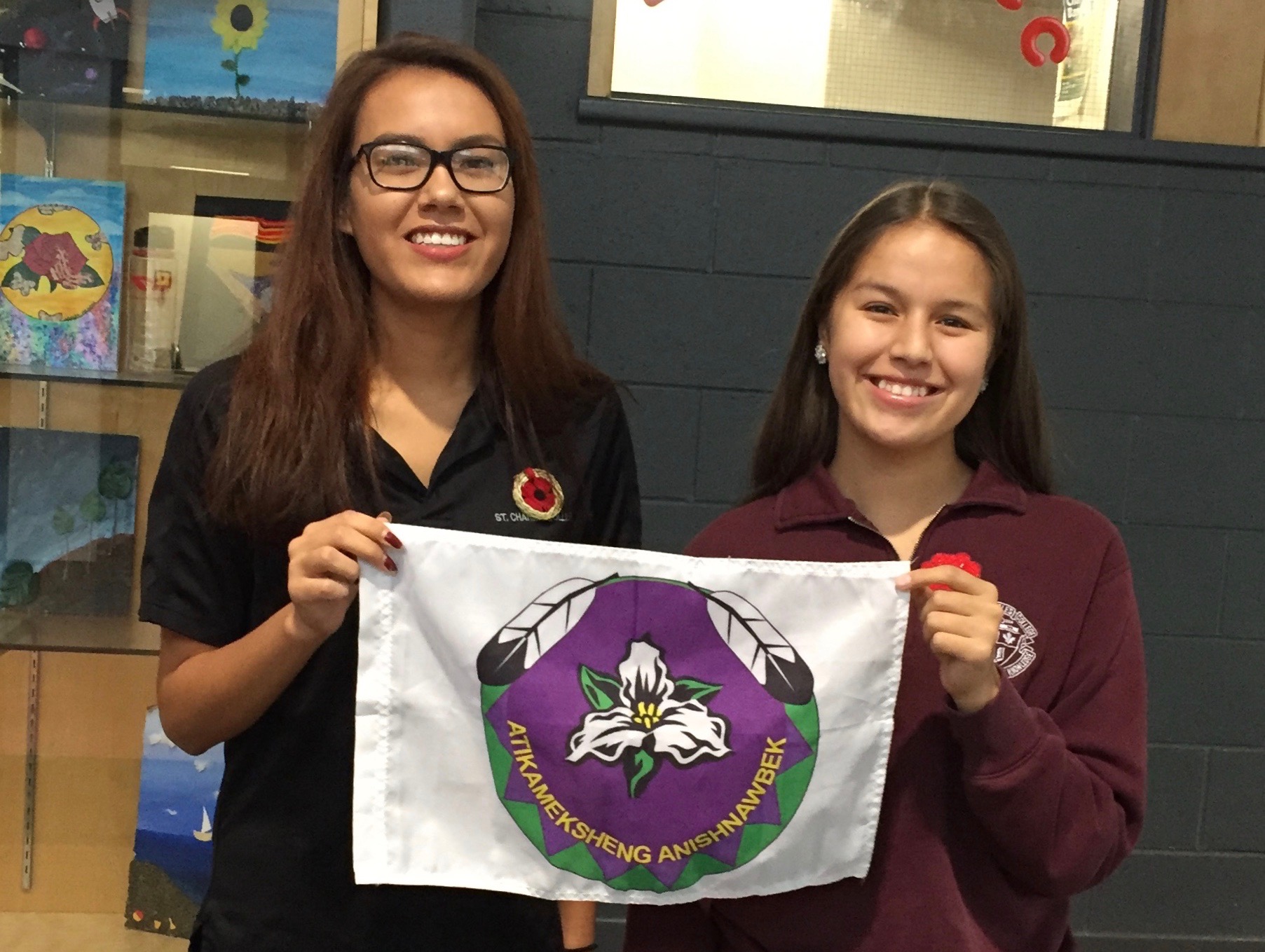 Two students hold the Atikameksheng Anishnawbek flag.